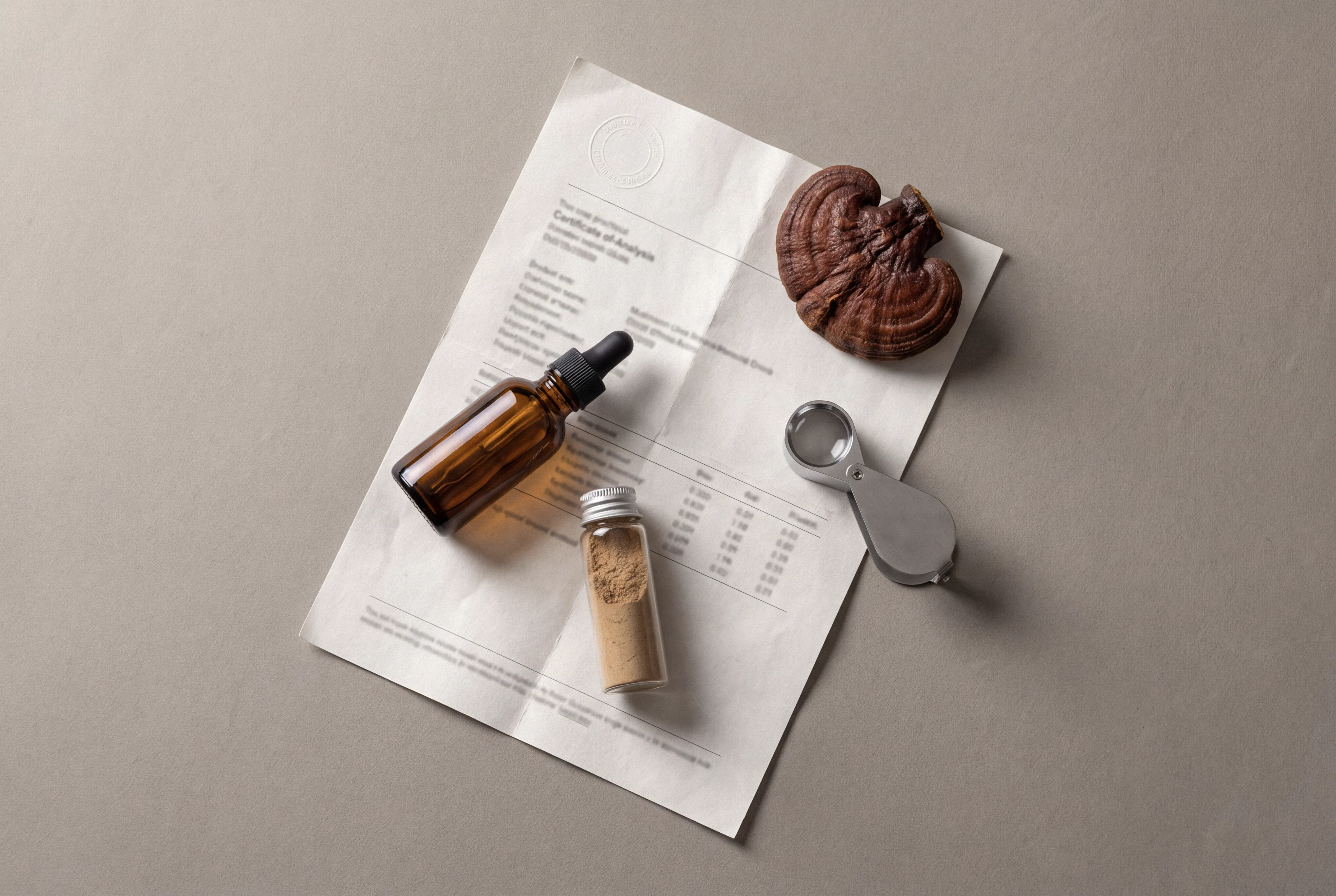 Mushroom tincture bottle, extract vial, and dried Reishi on a certificate of analysis