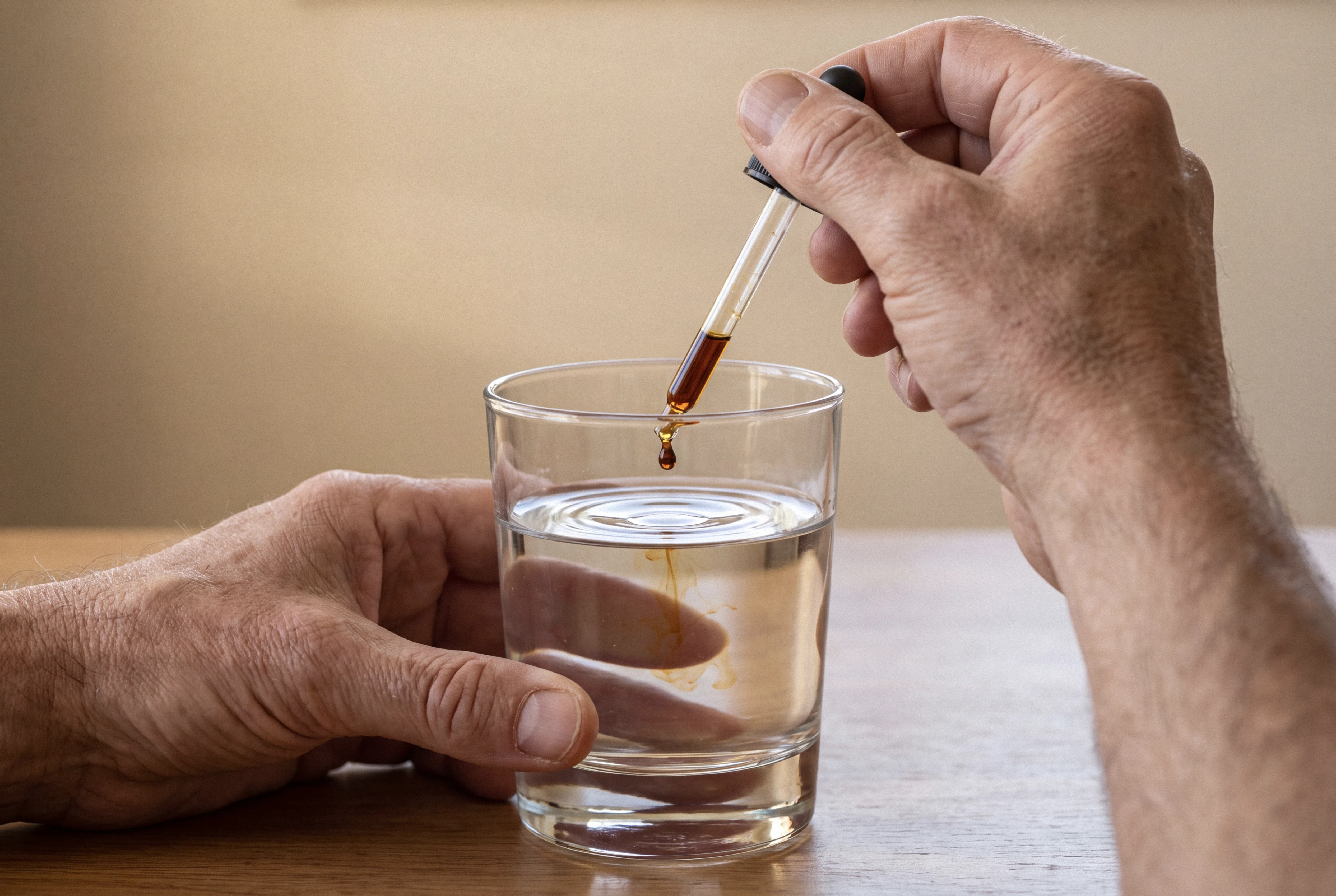 Dropper releasing mushroom extract into a glass of water