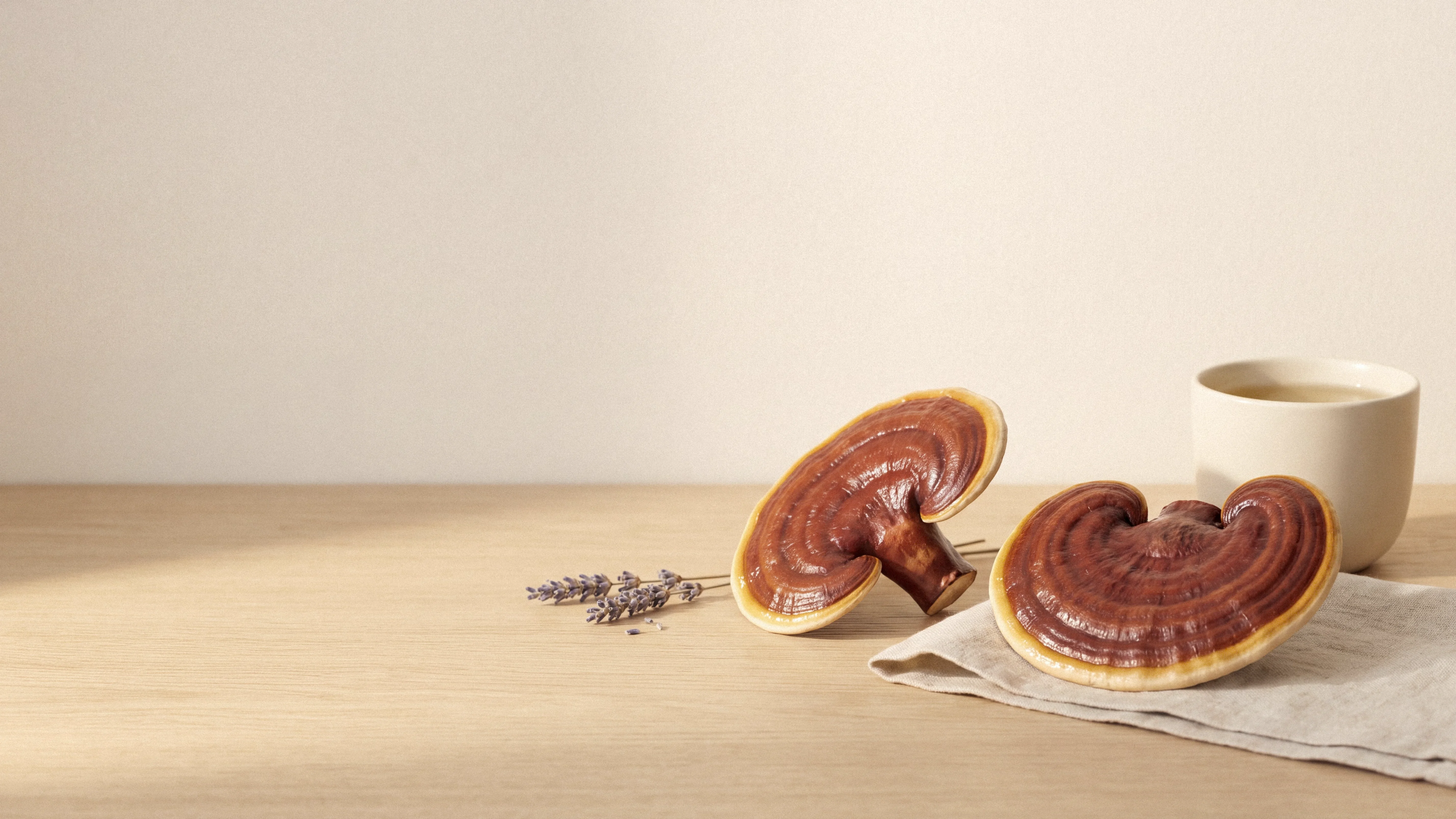 Two glossy reishi mushrooms besides a cup of hebal tea and lavender